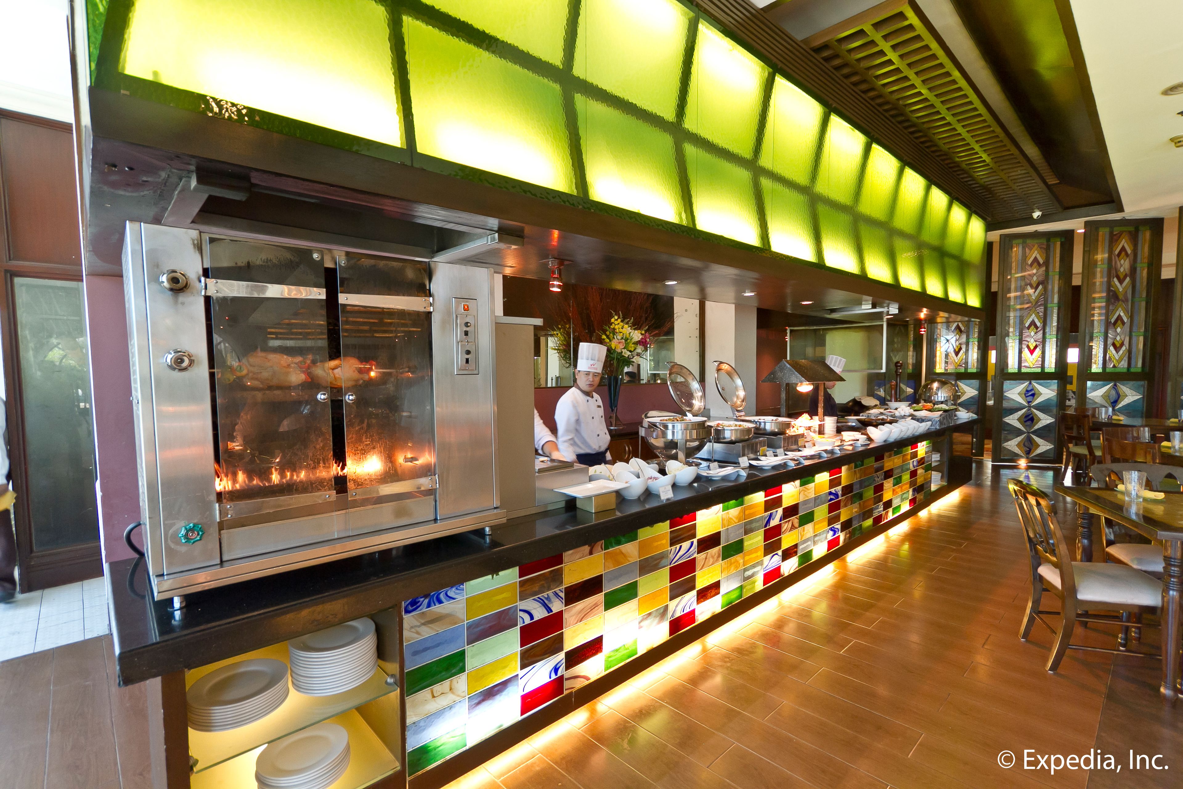 Un restaurante con una barra larga, salpicadero de azulejos y un cocinero preparando comida.