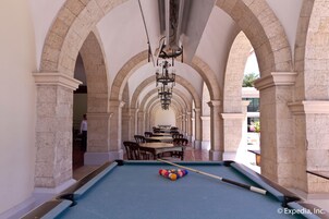 A pool table in a room with arched ceilings and stone columns.