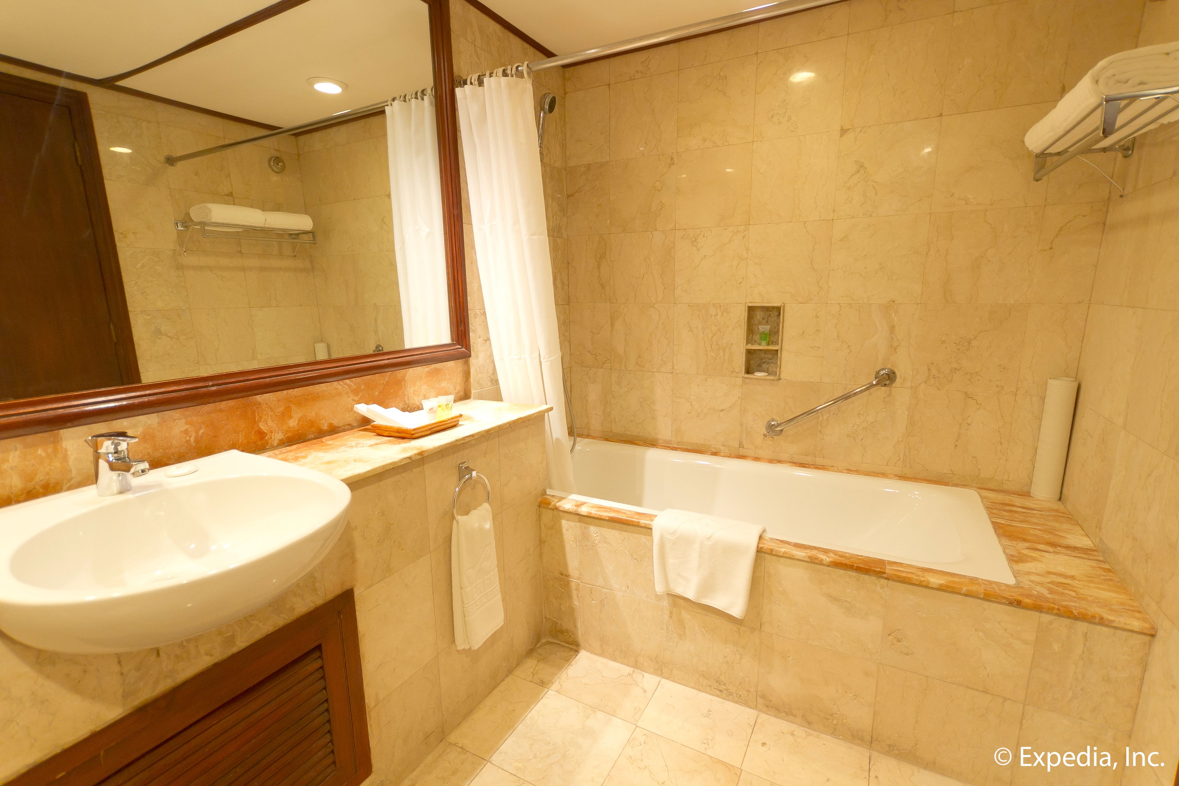Un baño con lavamanos, espejo, ducha y bañera.