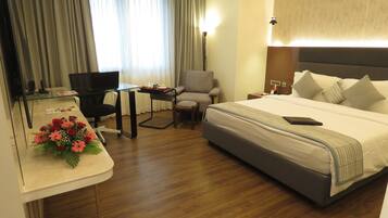 Ein Hotelzimmer mit einem Bett, einem Schreibtisch, einem Stuhl, einer Lampe und einem Fenster mit Vorhängen.