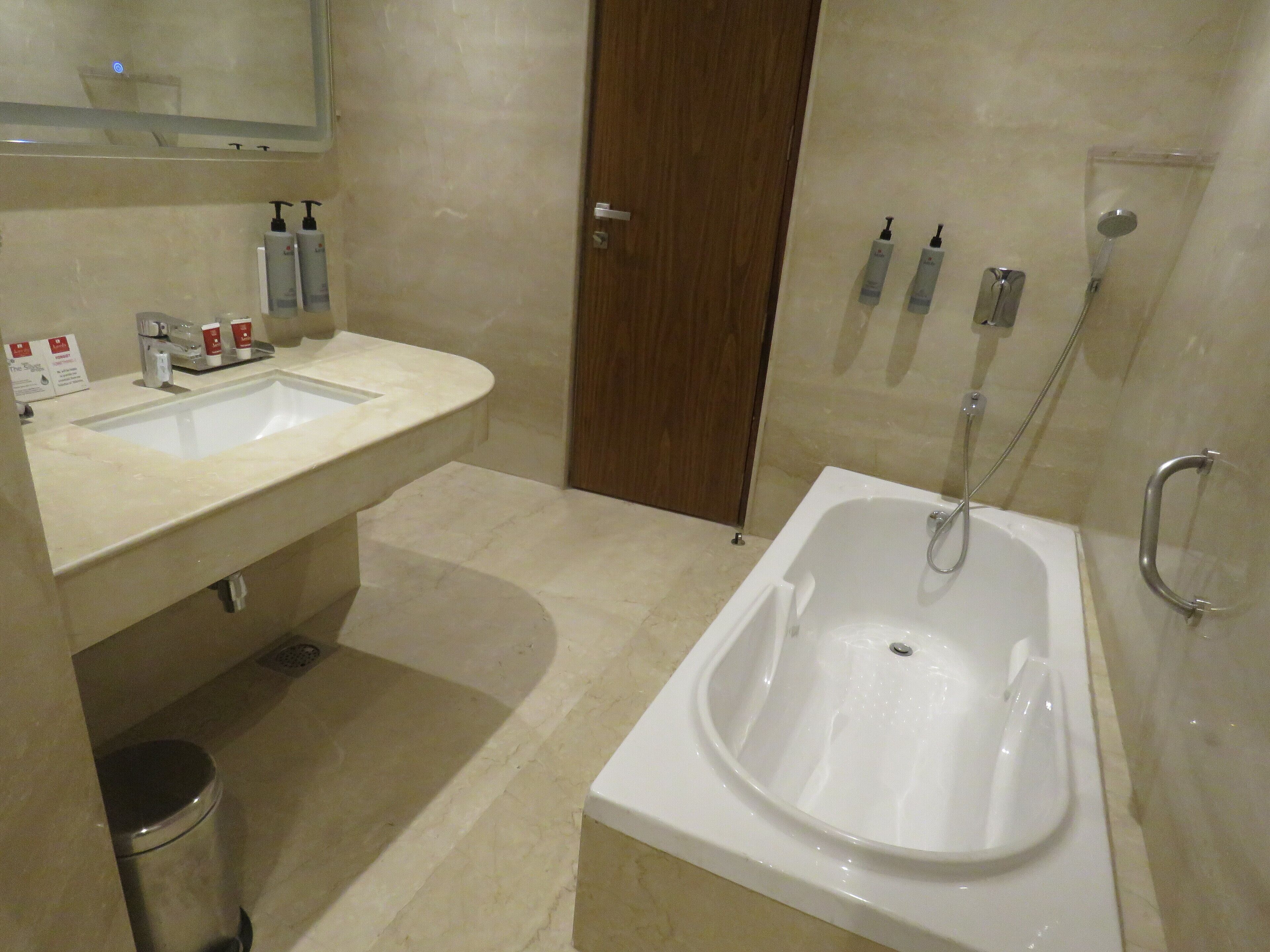 Ein modernes Badezimmer mit Waschbecken, Spiegel, Pflegeprodukten und einer Badewanne.