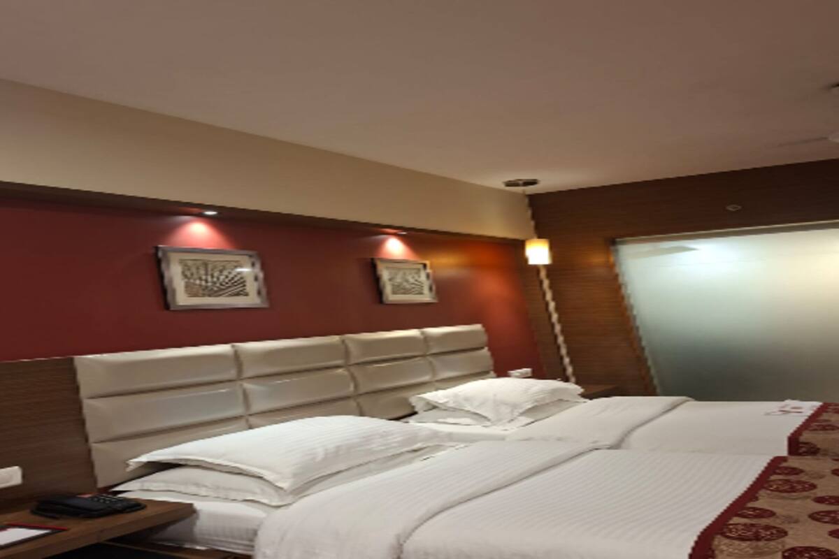Una habitación de hotel con una cama grande, una mesita de noche y una lámpara de pared.
