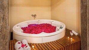 A jacuzzi with rose petals, wooden benches, and towels. - Lords Plaza, Surat (Surat)