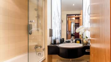 A modern bathroom with a glass-enclosed shower, a black vanity with a white sink, and a mirror with a decorative frame.