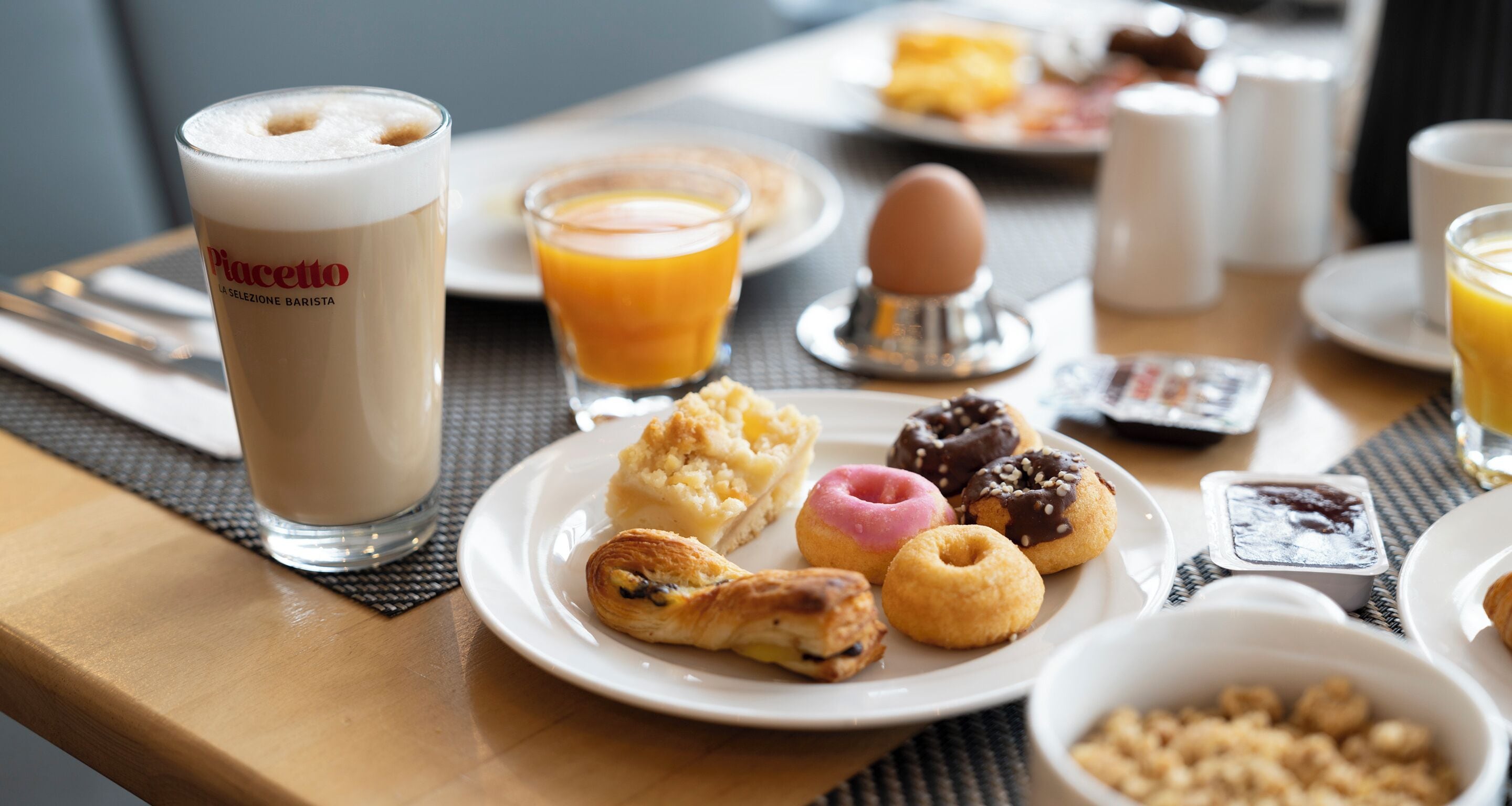 A breakfast setting with a plate of pastries, a glass of orange juice, and a cup of coffee.
