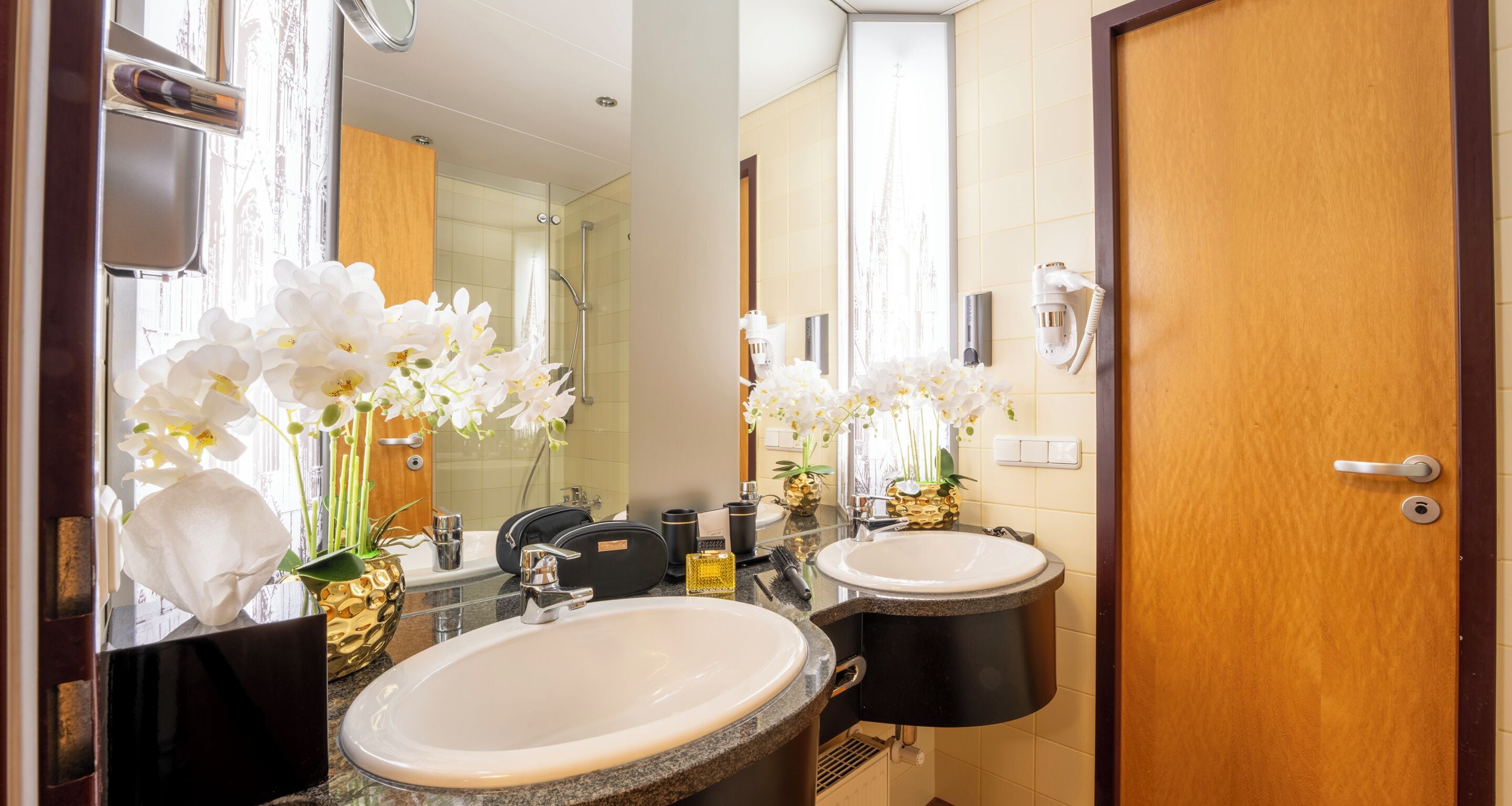 A bathroom with two sinks, a mirror, and a shower.