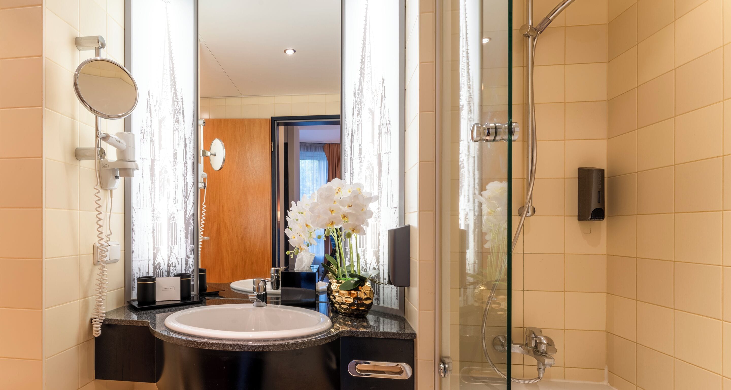 A bathroom with a sink, mirror, and shower.