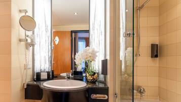 A bathroom with a sink, mirror, and shower.