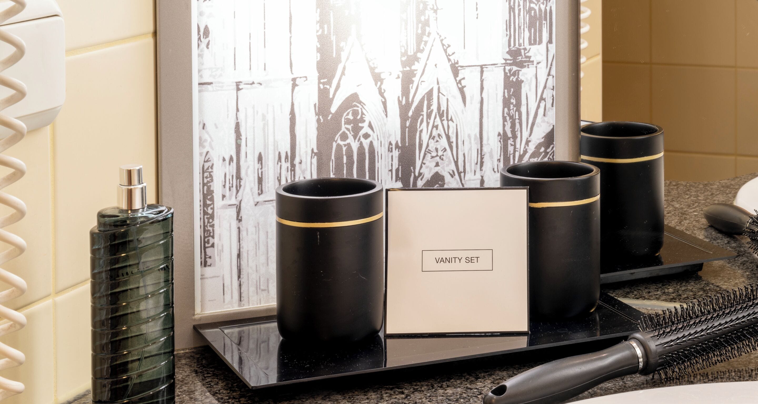 A vanity set with three black containers and a mirror.