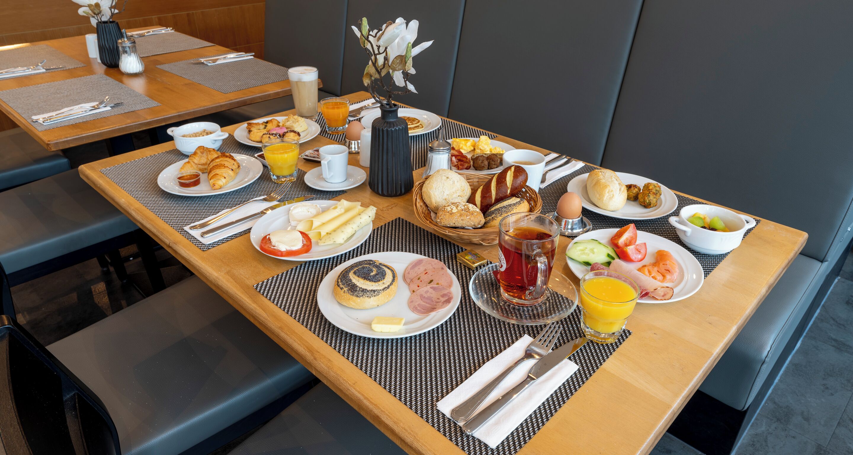 Une table de petit-déjeuner avec des croissants, des œufs et diverses confitures.