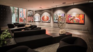 A modern art gallery with abstract paintings, black sofas, and a stone floor. - Penck Hotel Dresden (Dresden)
