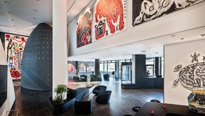 A modern lobby with abstract art on the walls, a seating area with sofas, and a reception desk. - Penck Hotel Dresden (Dresden)