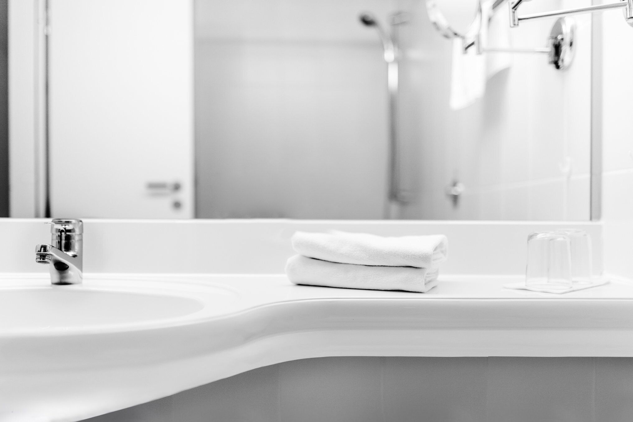 A bathroom with a white sink, a mirror, and a towel on the counter.