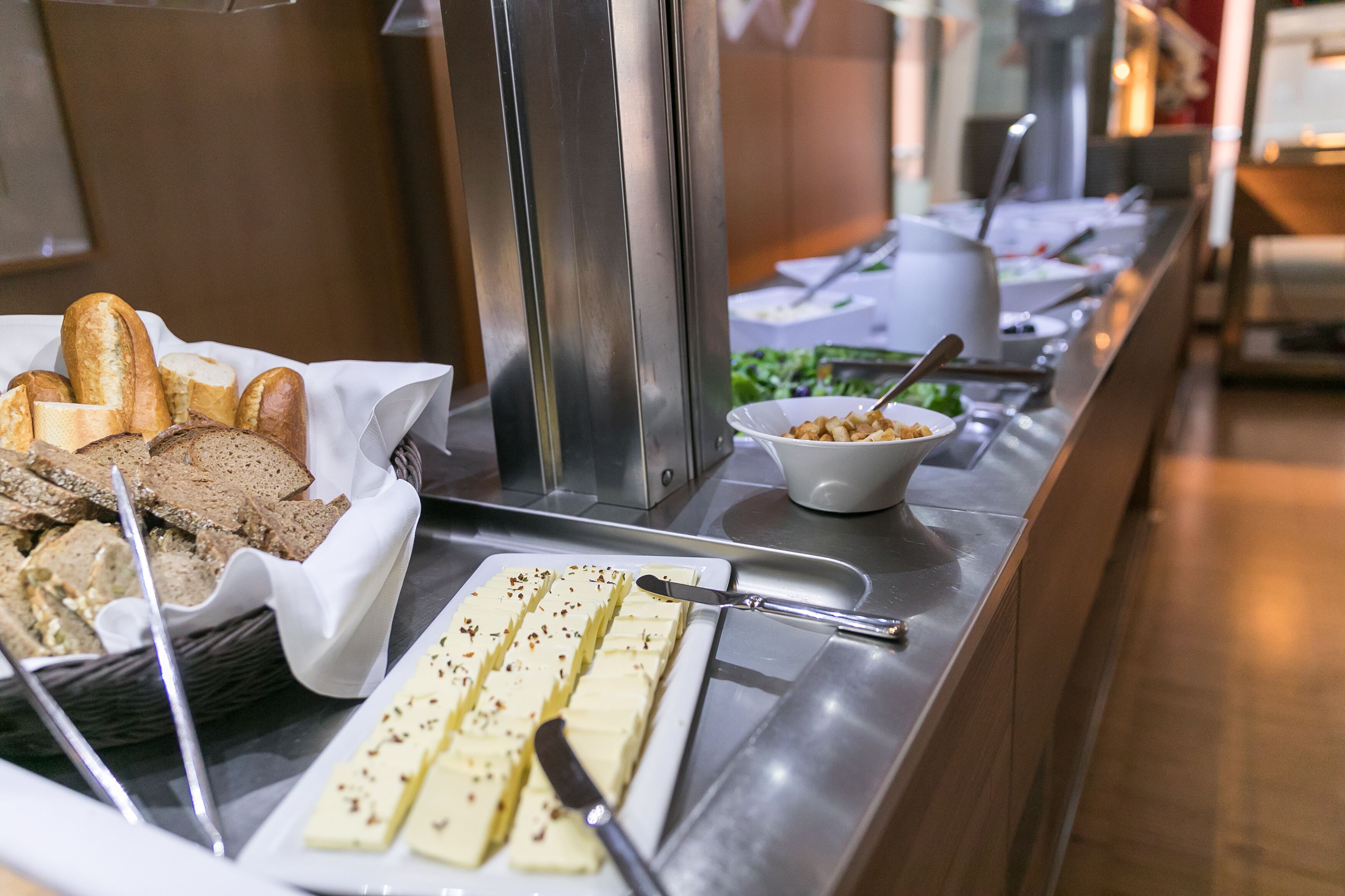 Un bufé con distintos alimentos, incluyendo pan, queso y ensalada.