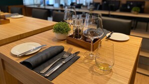 A dining area with a wooden table set for two, featuring a small potted plant, wine glasses, and cutlery. - TOP martas Hotel Lutherstadt-Wittenberg (Lutherstadt Wittenberg)