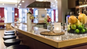 A bar area with a marble countertop, a vase with flowers, a candle, and a fruit bowl. - TOP martas Hotel Lutherstadt-Wittenberg (Lutherstadt Wittenberg)