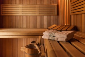 A sauna room with wooden benches, a towel, and a wooden bucket. - TOP martas Hotel Lutherstadt-Wittenberg (Lutherstadt Wittenberg)