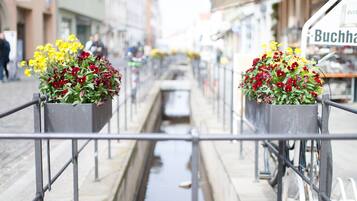 A canal with flower planters on the sides, a narrow waterway, and buildings in the background.