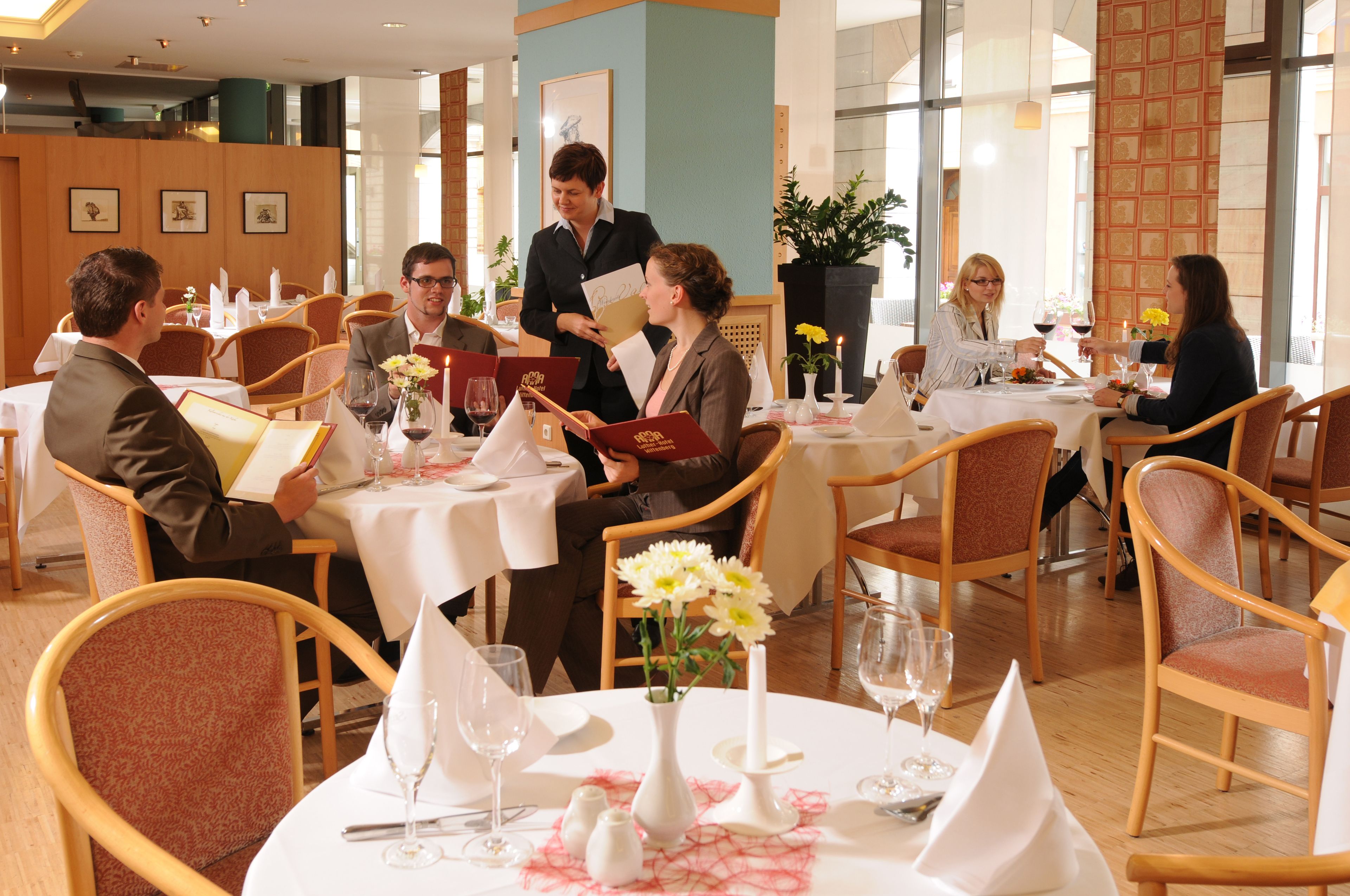 Un restaurant avec des tables rondes, des nappes blanches et des chaises en bois.