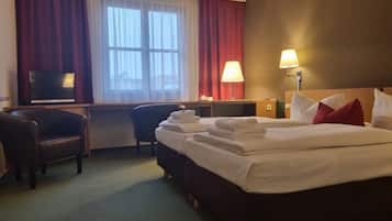 Ein Hotelzimmer mit Bett, Schreibtisch, Stuhl, Fernseher und Lampe.