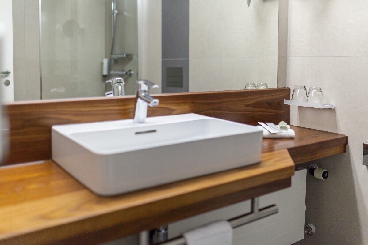 Un baño con lavamanos blanco, encimera de madera y espejo.