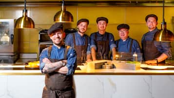 Un grupo de cocineros en una cocina con encimeras de mármol e iluminación colgante.