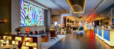 Experience the vibrant atmosphere of our lobby, featuring a striking geometric artwork and a stylish reception area with comfortable seating.