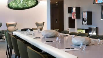 A modern conference room with a long table, multiple chairs, and a unique geometric light fixture.