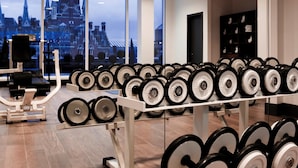 A gym with weightlifting equipment and a large window with a cityscape view. - Pullman London St Pancras (London)