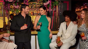 A bar area with a decorative backdrop of flowers and bottles.