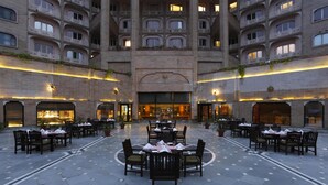 A spacious courtyard with multiple dining tables and chairs, surrounded by a high-rise building with balconies. - Park Plaza Ludhiana (Ludhiana)