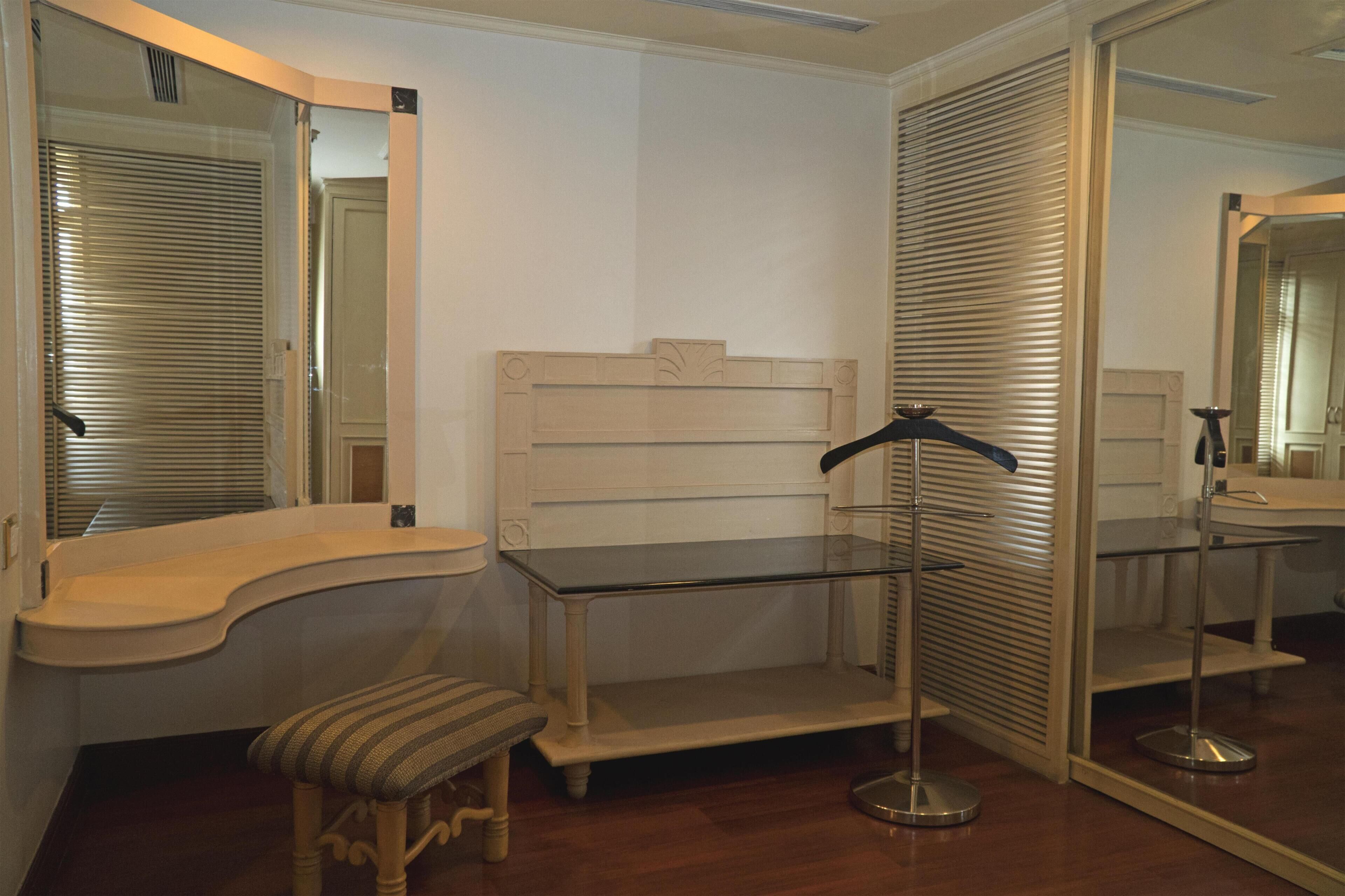 Una habitación con un banco de madera, una mesa de cristal y un espejo.