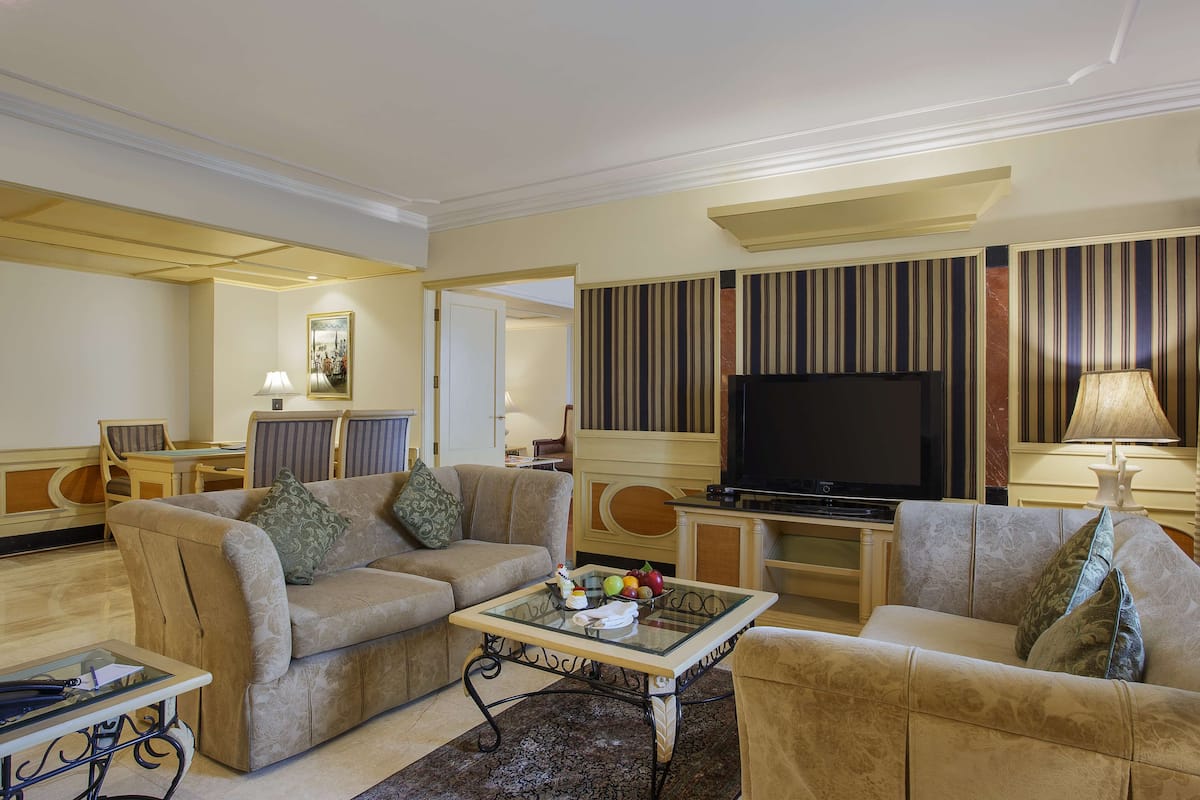 A living room with a sofa, armchairs, a coffee table, a TV, and a dining area with a table and chairs.