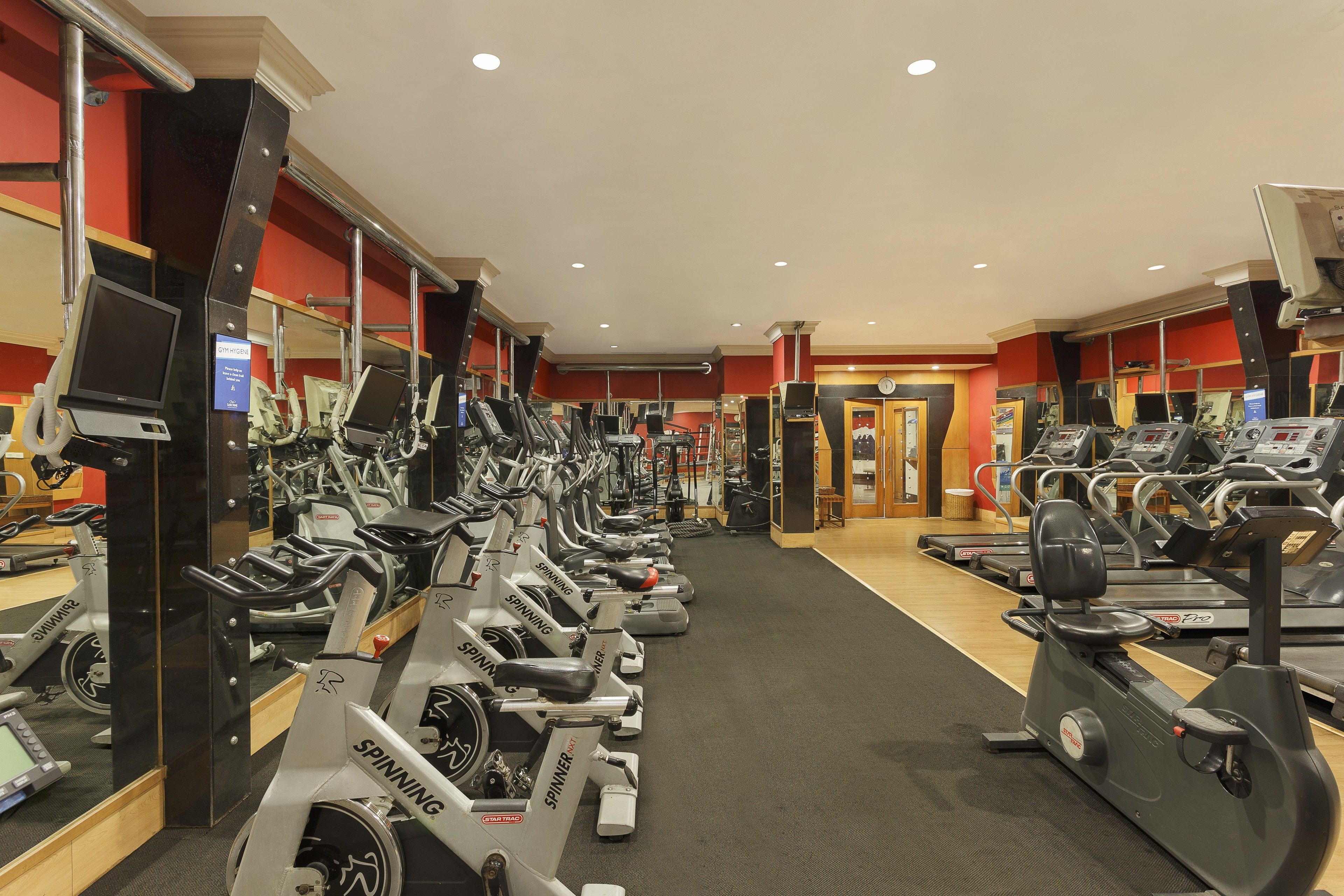 Une salle de sport équipée de plusieurs vélos d’appartement et de tapis de course disposés en rangées.