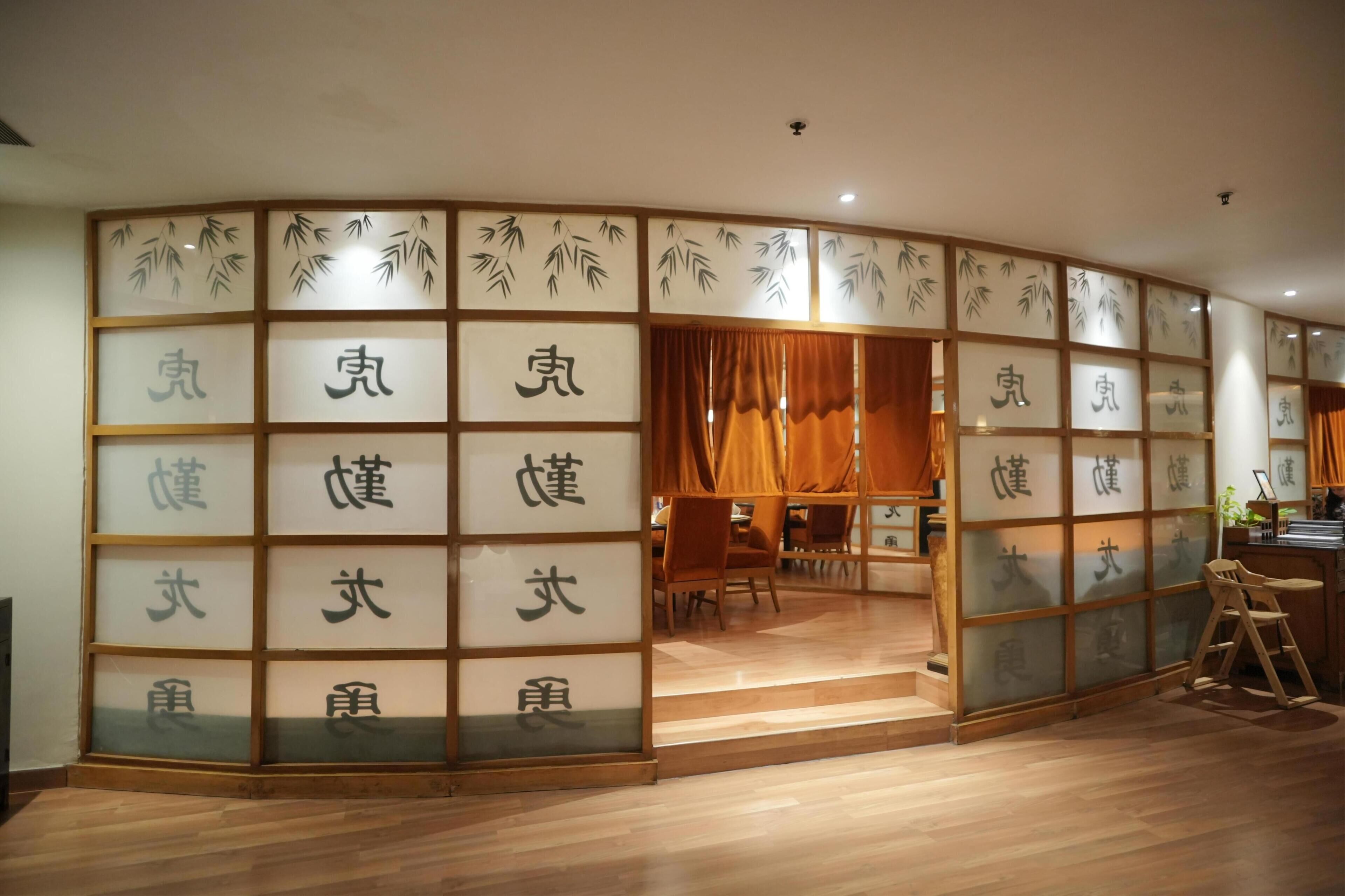 Ein traditioneller japanischer Raum mit Tatami-Bodenbelag, Schiebetüren mit Kalligraphie und einem niedrigen Holztisch.