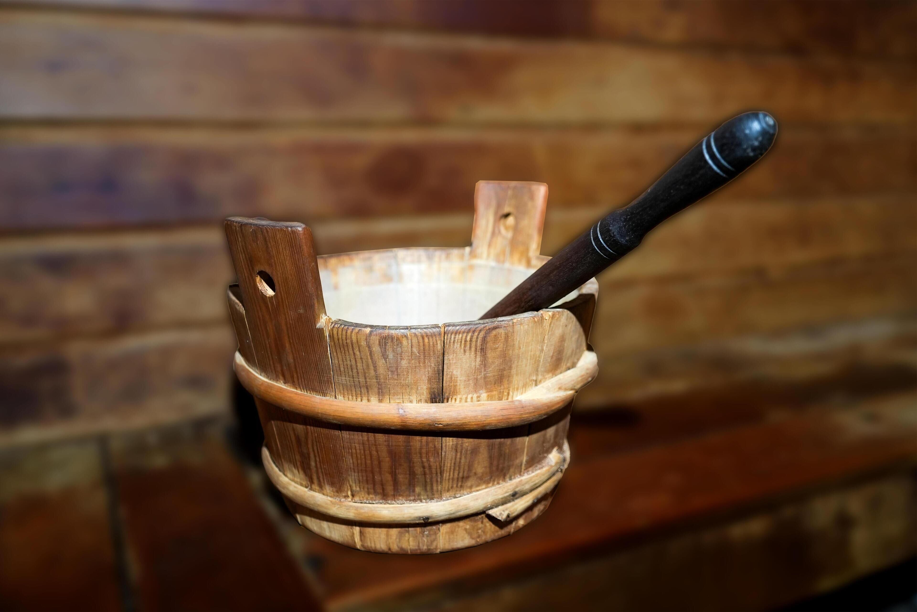 A wooden bowl with a handle, placed on a wooden surface.