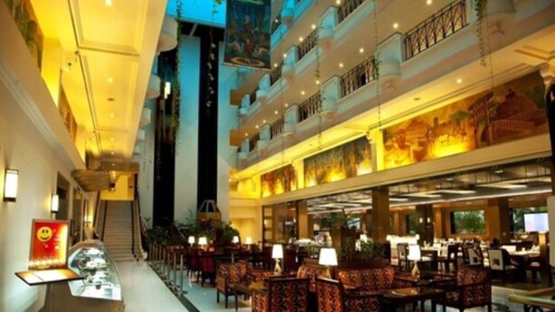 A multi-level hotel lobby with a central staircase, seating areas, and a reception desk.