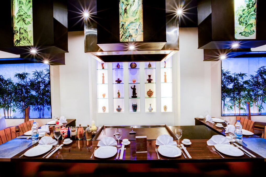 Un restaurant avec une longue table à manger dressée pour le repas, entourée de chaises.