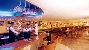 A bar area with a pool table, bar stools, and a counter with a bartender.