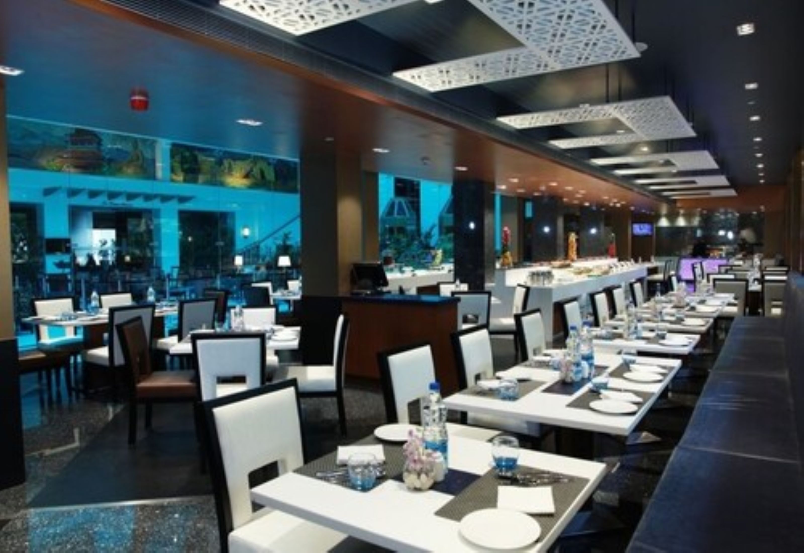A modern dining area with long tables, chairs, and a central counter.