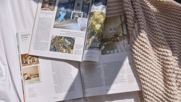 Ein Buch liegt auf einem Bett, dazu eine gestrickte Decke.