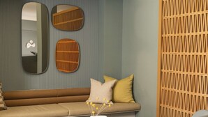 Un soggiorno moderno con un divano, due poltrone, un tavolino rotondo e specchi decorativi.