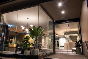 A modern hotel lobby with glass walls, a reception desk, and potted plants.