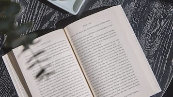 An open book on a round table with a cup of coffee and a spoon.
