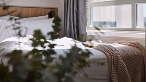 Un letto rifatto con un copriletto bianco e una coperta lavorata color beige.
