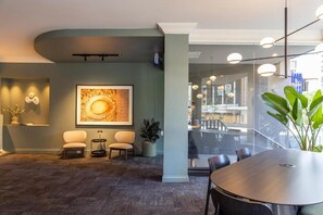 A modern interior with a round table, two chairs, a large framed artwork, and a potted plant.