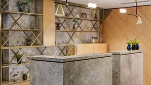 A reception desk with a marble top, flanked by shelves with plants and decorative items. - Park Plaza Utrecht (Utrecht)