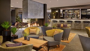 A modern lounge area with seating, a fireplace, and a bar with various bottles. - Park Plaza Utrecht (Utrecht)