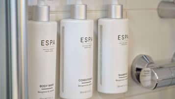 Three bottles of ESPA body wash, conditioner, and shampoo in a bathroom.