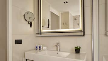 Un baño moderno con un espejo grande, un lavamanos y artículos de aseo.
